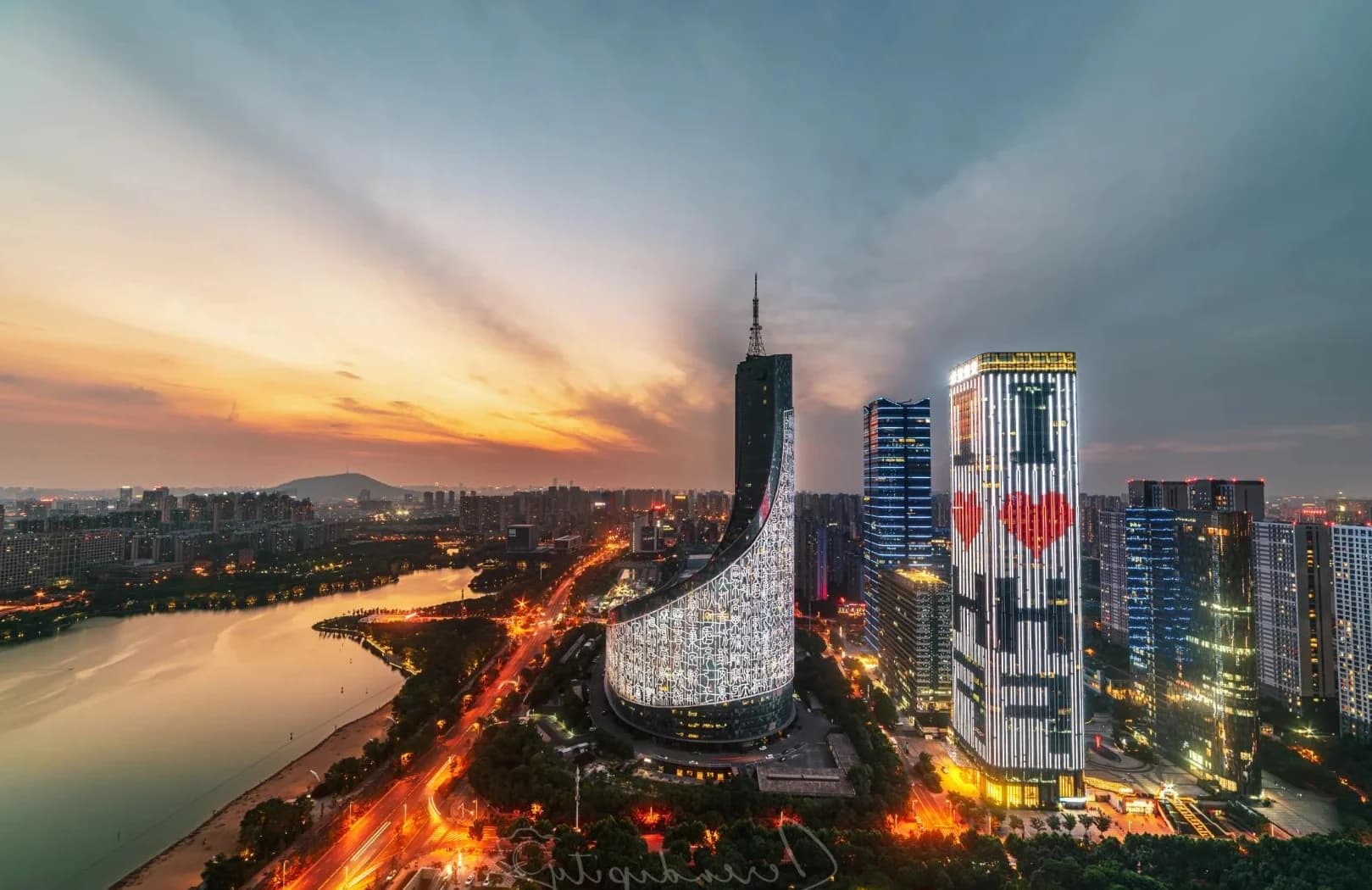 Hefei skyline at sunset, with Swan Lake and illuminated towers in the foreground