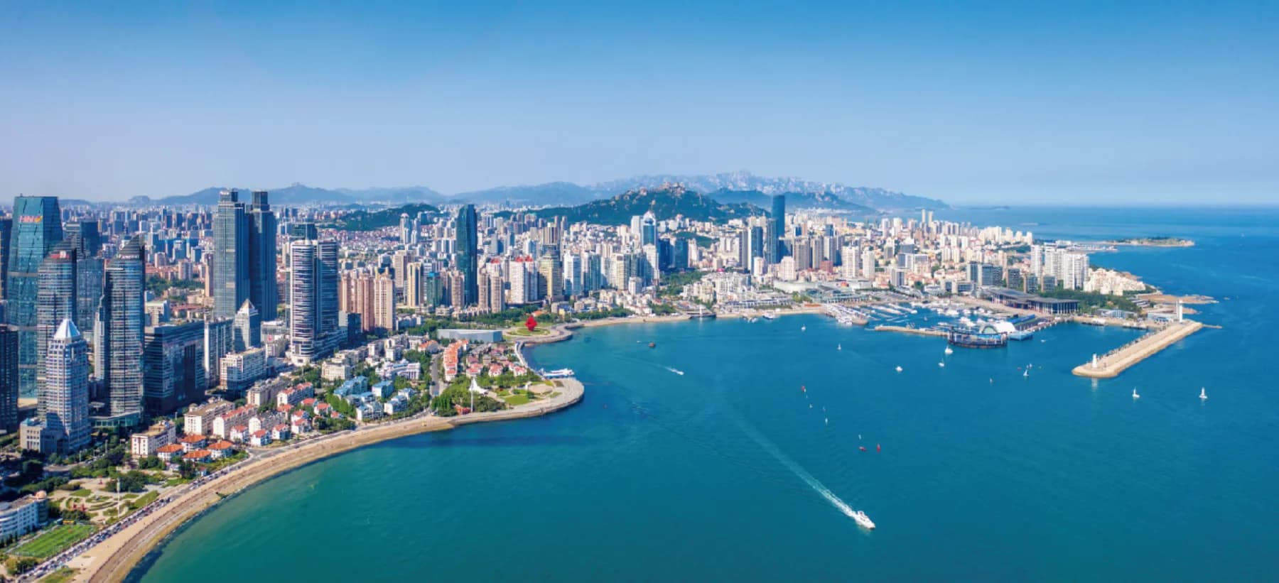 Aerial view of the Qingdao waterfront, with the city skyline curving around Fushan Bay